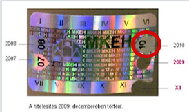 A képen egy matrica látható, pirossal bekarikázva a rajta lévő hitelesítési évet, mely a matrica jobb felső részében található.