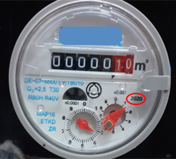 A képen egy vízmérő óra számlapja látható, melynél a hitelesítési év középen jobb oldalt található.