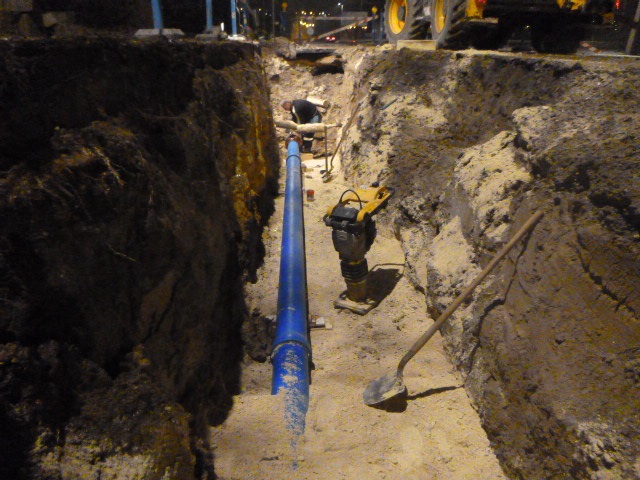 A képen a lefektetett új csővezeték és a betemetéséhez szükséges munkagépek láthatók.