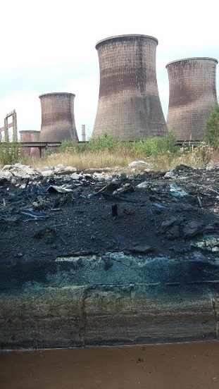 The picture depicts a nuclear power plant. Close to it, there is a hole digged into the earth.