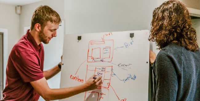 A kép illusztráció, amin két személy egy flipchart papíron folyamatábrát tervez.