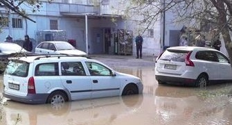 A képen csősérülés utáni utcakép látható, vízben álló autókkal, és úttesttel.