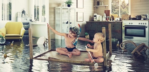 A képen két kétév körüli gyermek látható egy emelvényen ülve, mert alattuk a  helyiség egésze víz alatt van.