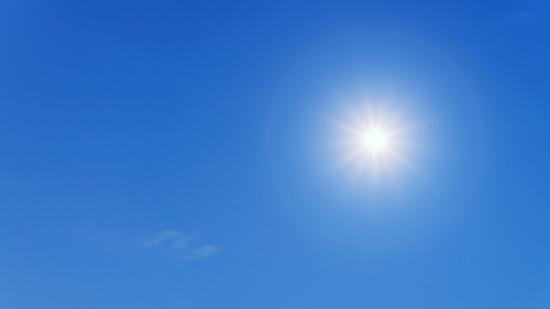 A kép illusztráció, melyen a kék ég látható szikrázó napsütéssel.