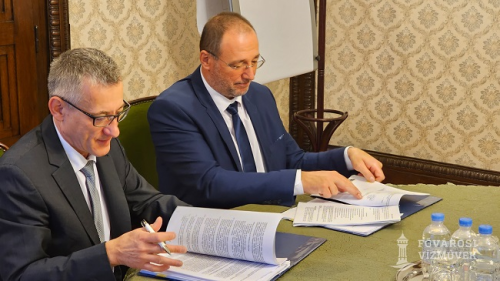 A képen Bolla Tibor és Csörnyei Géza látható, a szerződés aláírása közbeni pillanatokban, amely a BKV Zrt. és a Fővárosi Vízművek között köttetett.